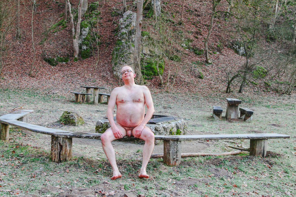 Naked man sitting with his legs wide spread