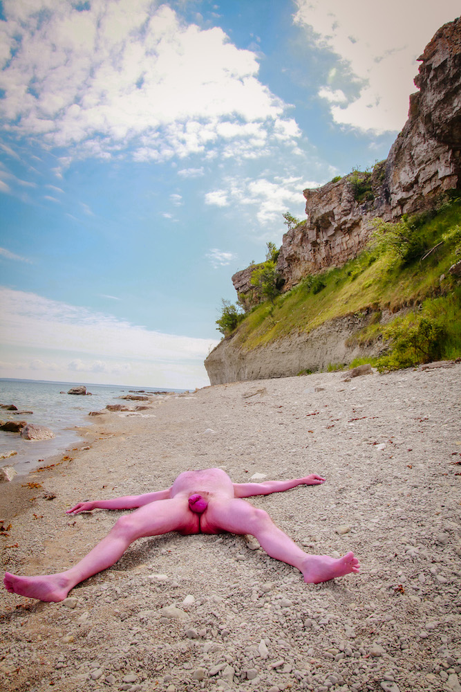 Male nude on Gotland lying on a stony beach exposing his penis and testis